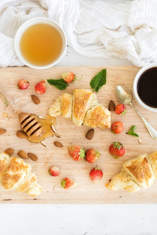 Круассаны, мед, свежие ягоды клубники и кофе на завтрак