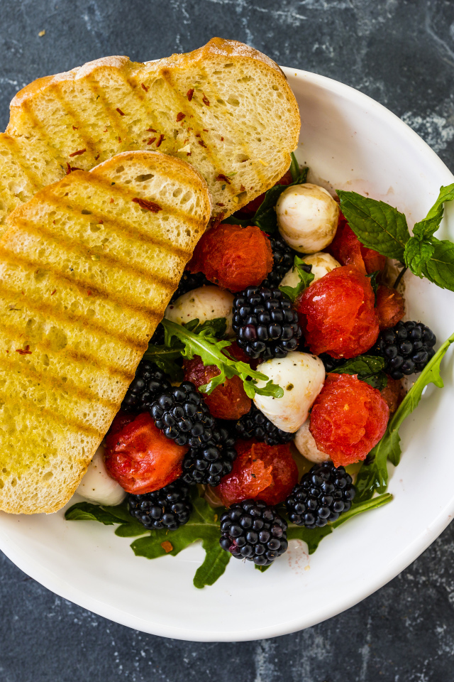 Гренки с салатом из ягод на белой тарелке