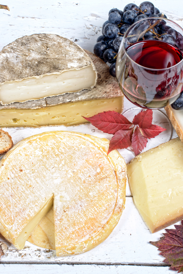 Дорогой сыр с плесенью на столе с виноградом и красным вином