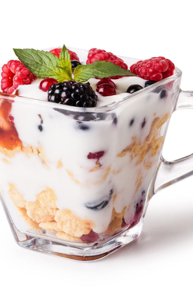 Хлопья с йогуртом и ягодами в стакане на белом фоне