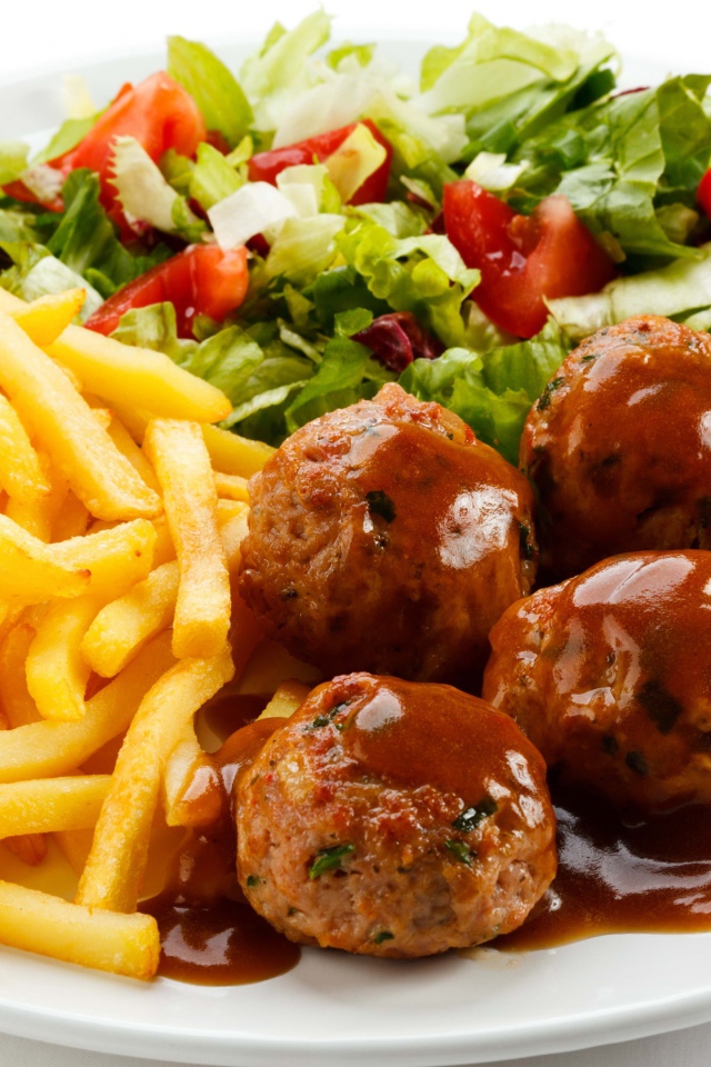 Картофель фри на белой тарелке с салатом и фрикадельками