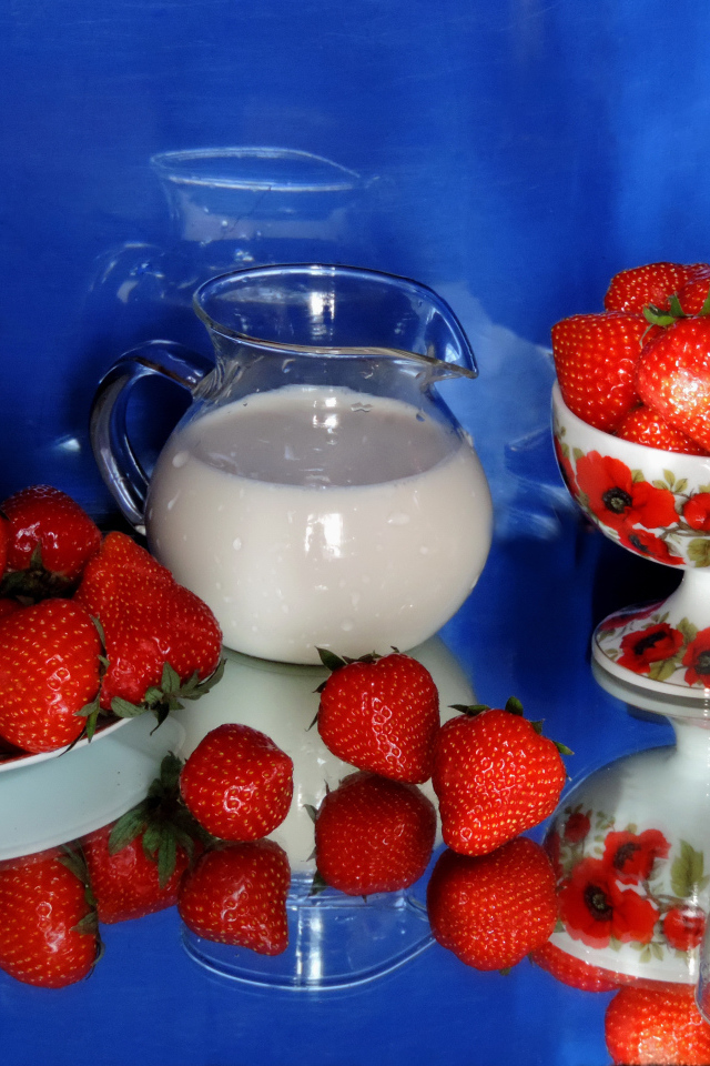 Свежие аппетитные ягоды клубники на столе с молоком