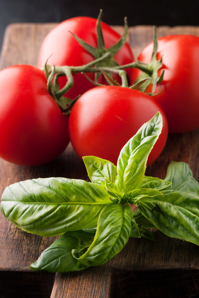 Свежие помидоры на разделочной с зеленью