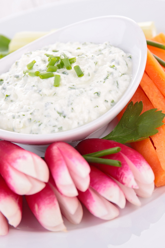 Свежие овощи с соусом в белой тарелке 