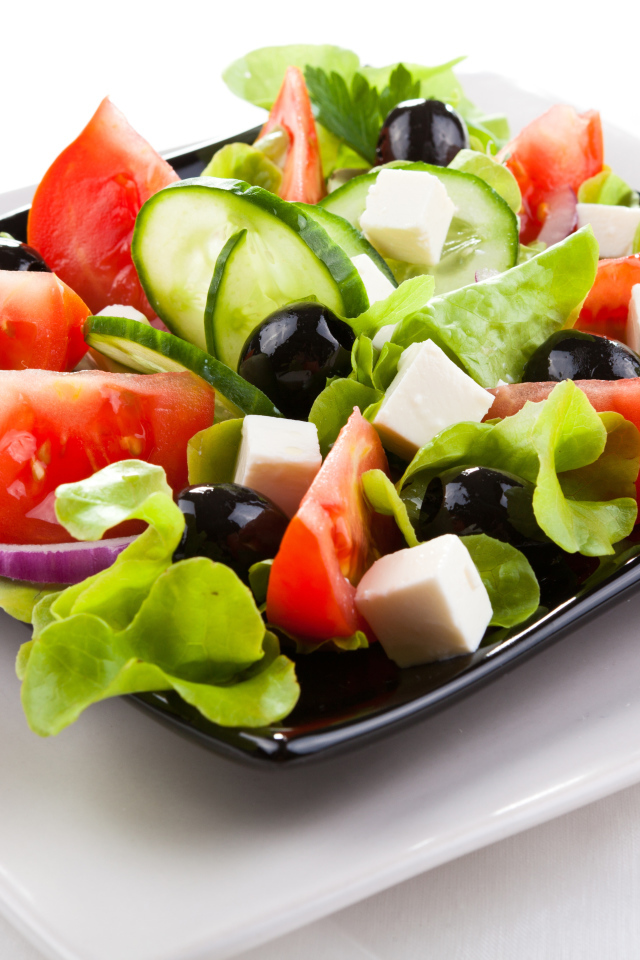 Греческий салат с сыром, помидорами и огурцами на белом фоне