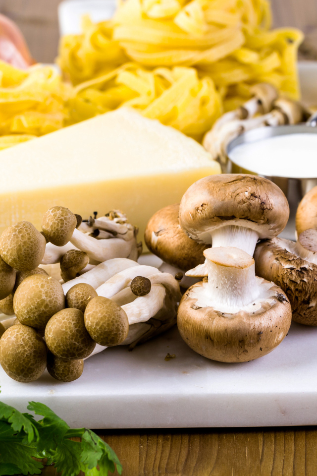 Грибы на разделочной доске с сыром, макаронами и зеленью