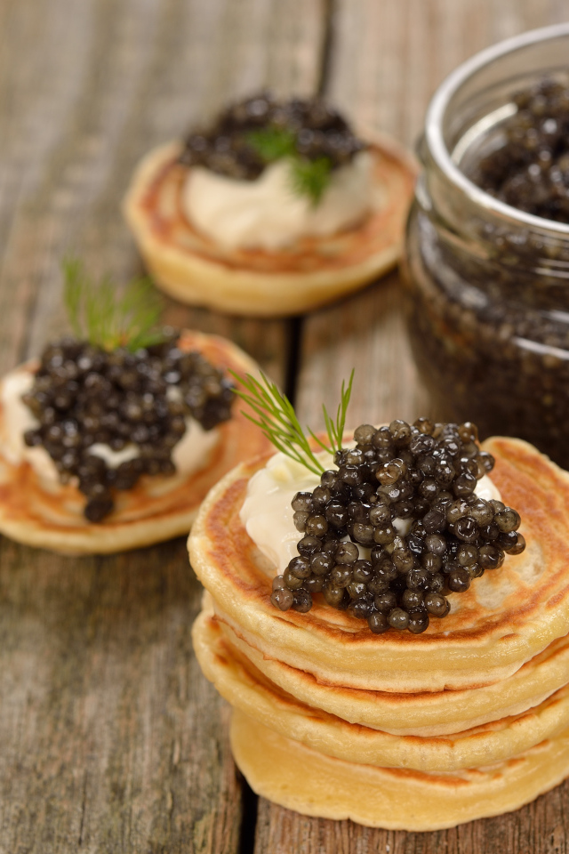 Оладьи с икрой и зеленью на столе