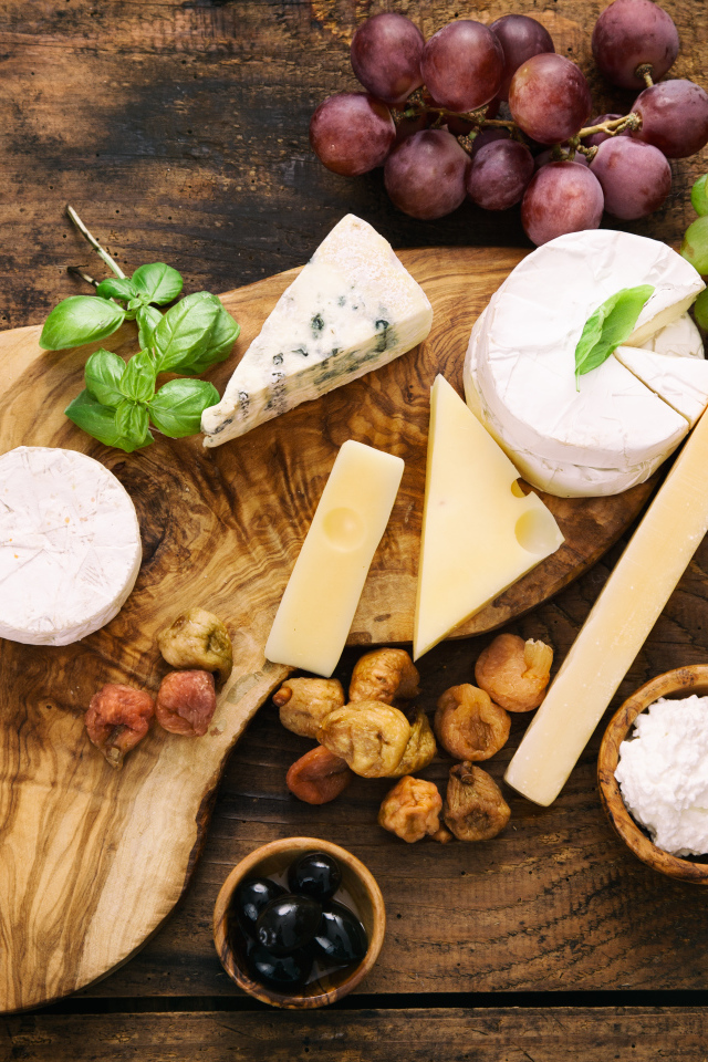 Кусочки сыра с виноградом и оливками на столе