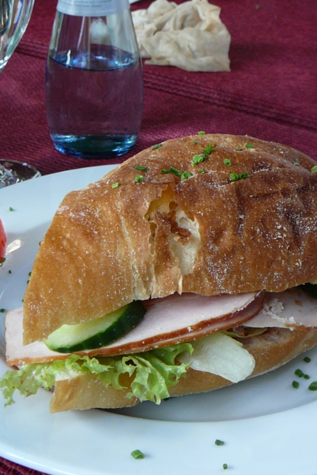 Сэндвич с ветчиной и овощами на столе в ресторане