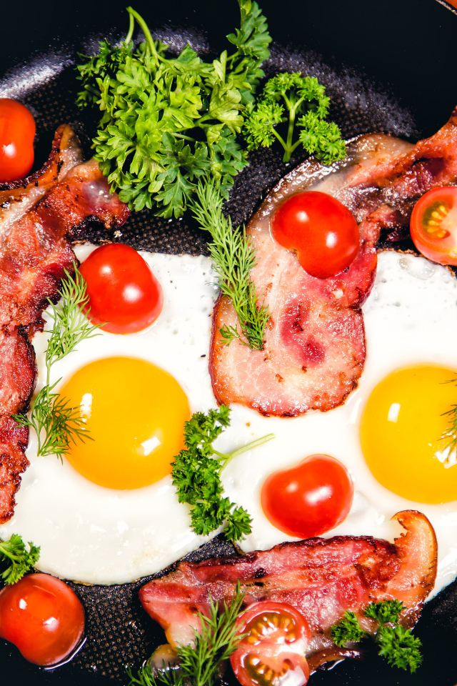 Яичница с беконом, помидорами и зеленью в сковороде на завтрак