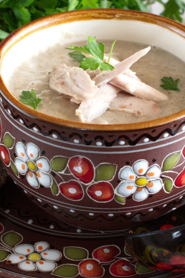 Суп с курицей в красивой тарелке на столе с черным хлебом