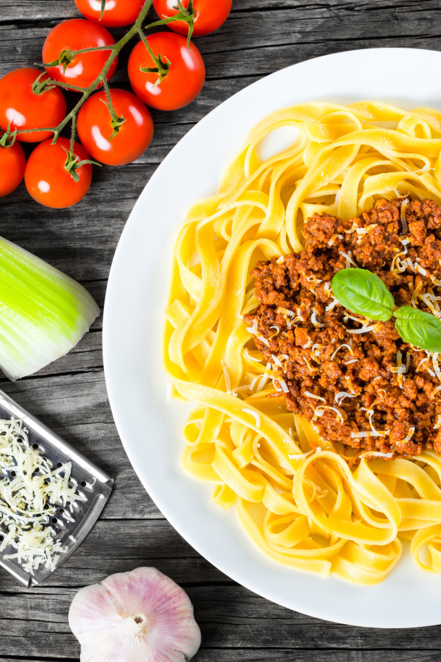 Спагетти на белой тарелке с мясом и сыром