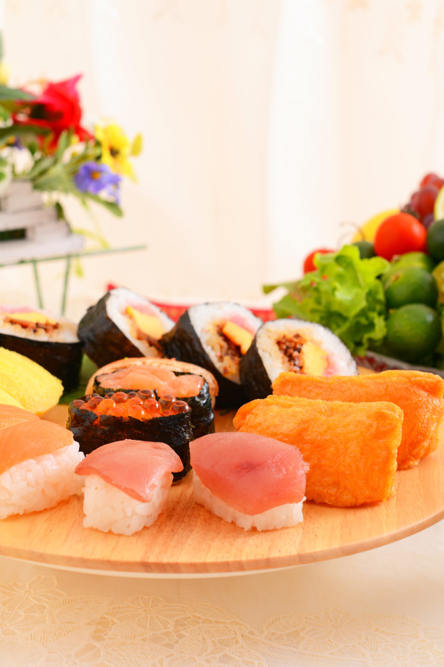 Суши на столе с фруктами и салатом из овощей