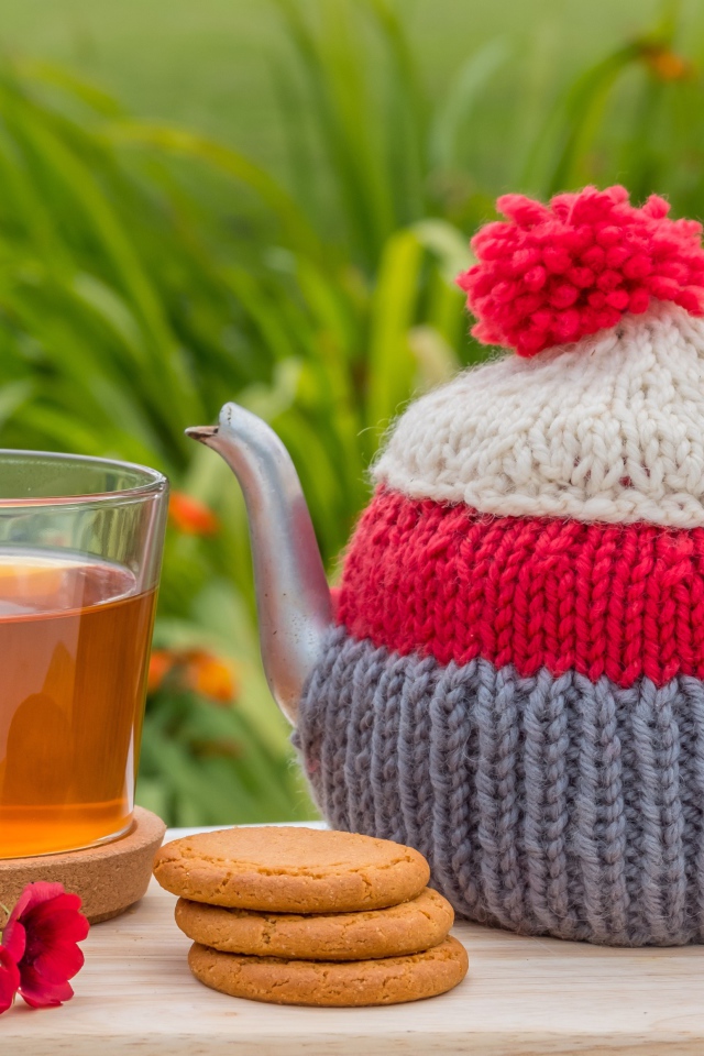 Чайник с чашкой чая на столе с печеньем и цветами