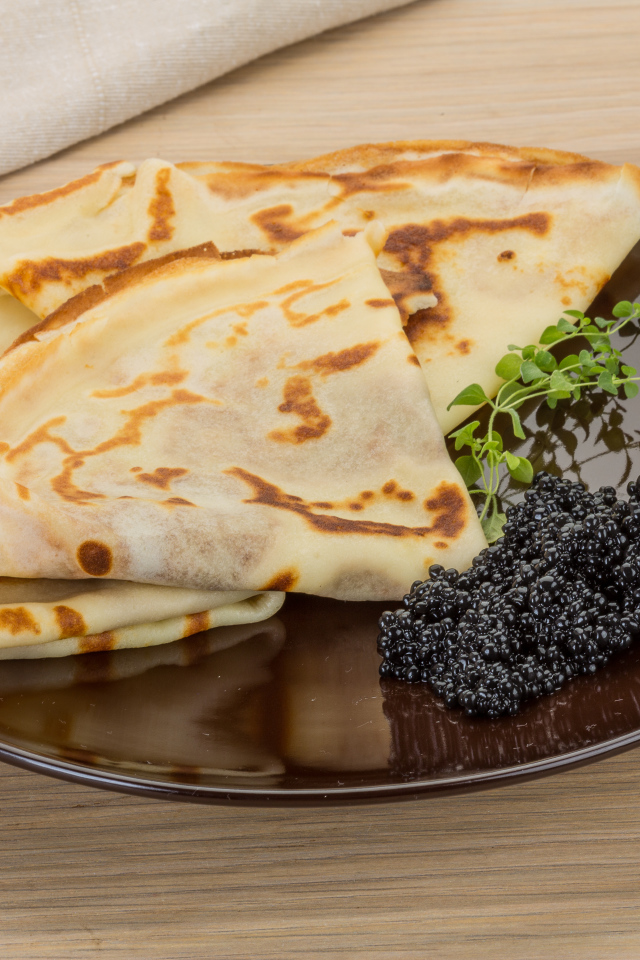 Тонкие блины на тарелке с черной икрой