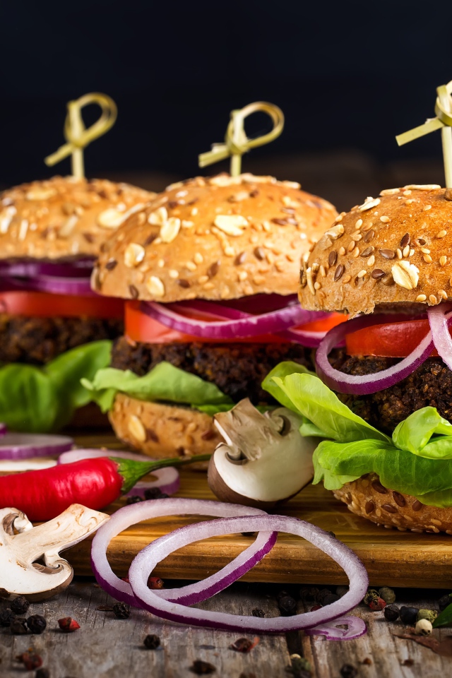 Три аппетитных гамбургера с кольцами лука и перцем