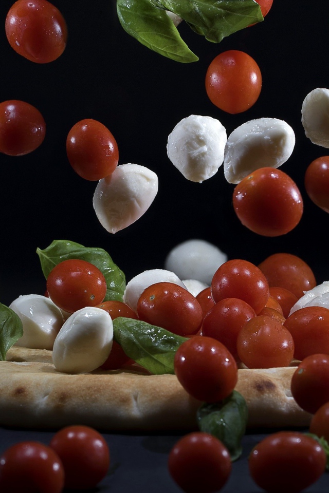 Помидоры и сыр Моцарелла падают на пиццу 