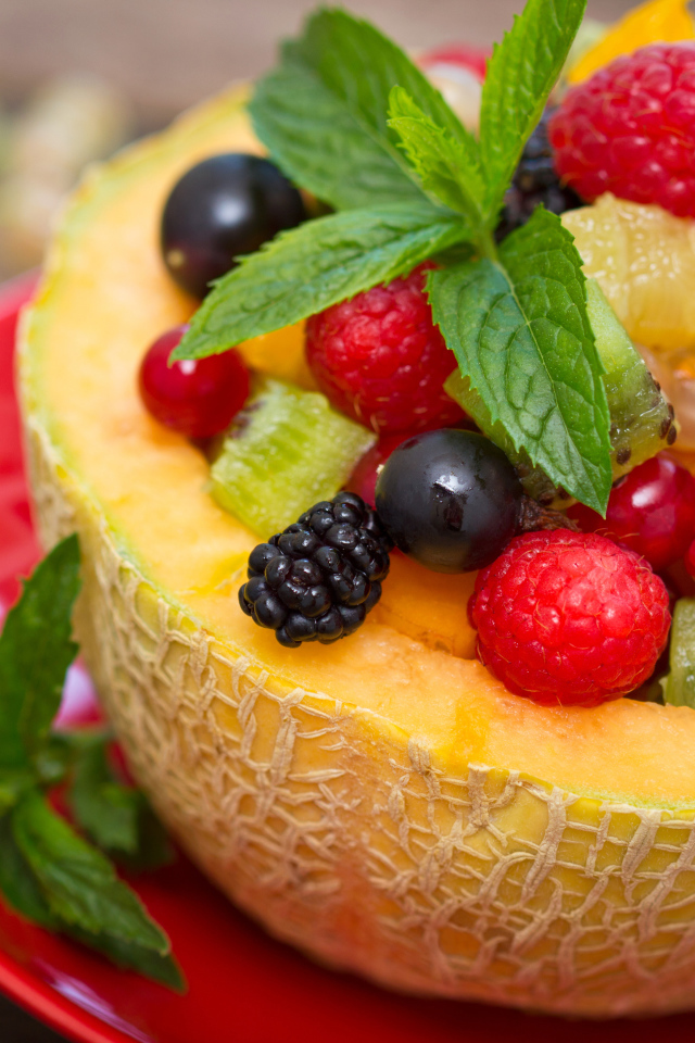 Аппетитные свежие ягоды с листьями мяты в половине дыни