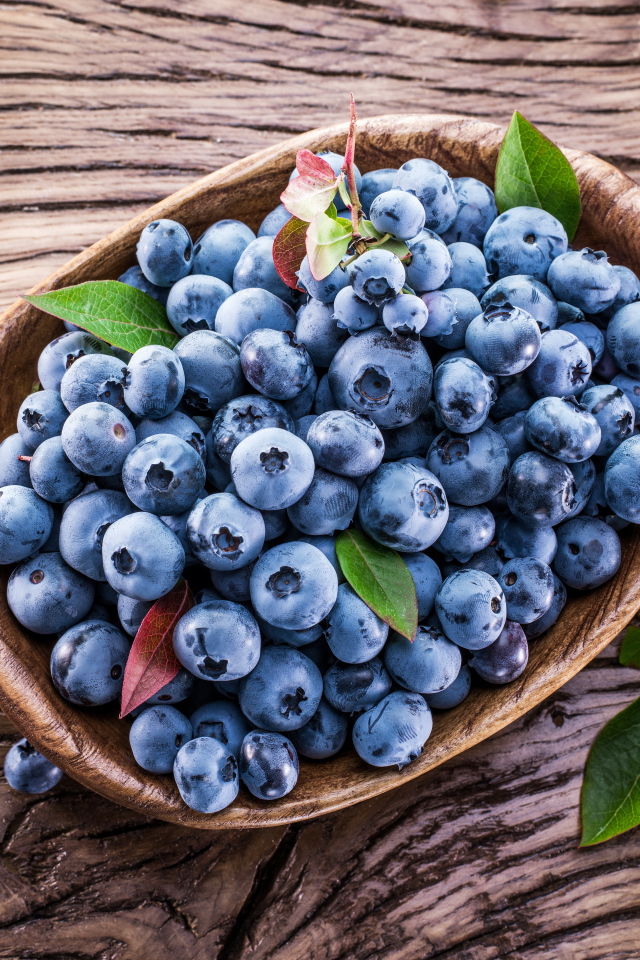 Ягоды свежей черники в тарелке на деревянном столе