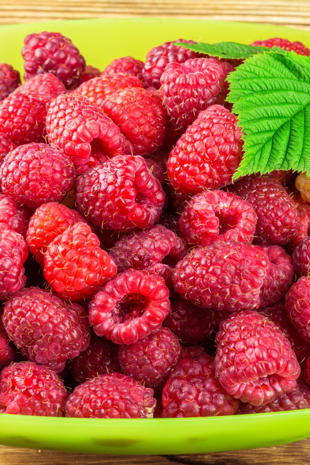 Свежая малина в зеленой миске на столе