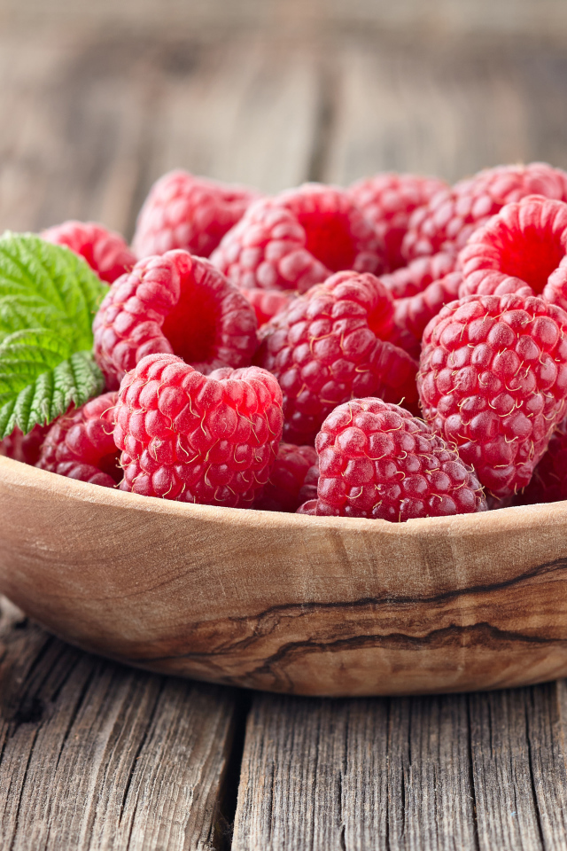 Крупные спелые ягоды малины в деревянной миске на столе