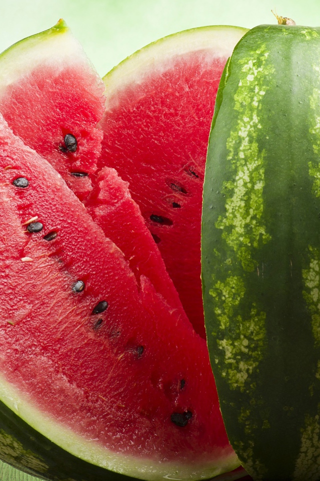 Большой спелый арбуз нарезанный скибками  на столе