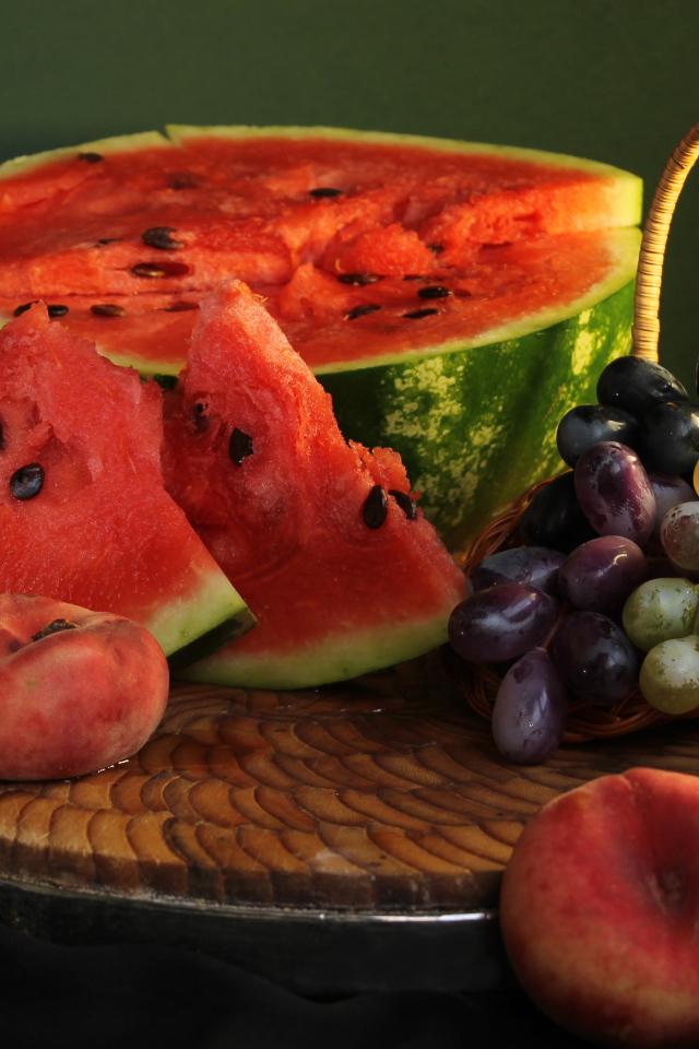Нарезанный арбуз на столе с виноградом и персиками