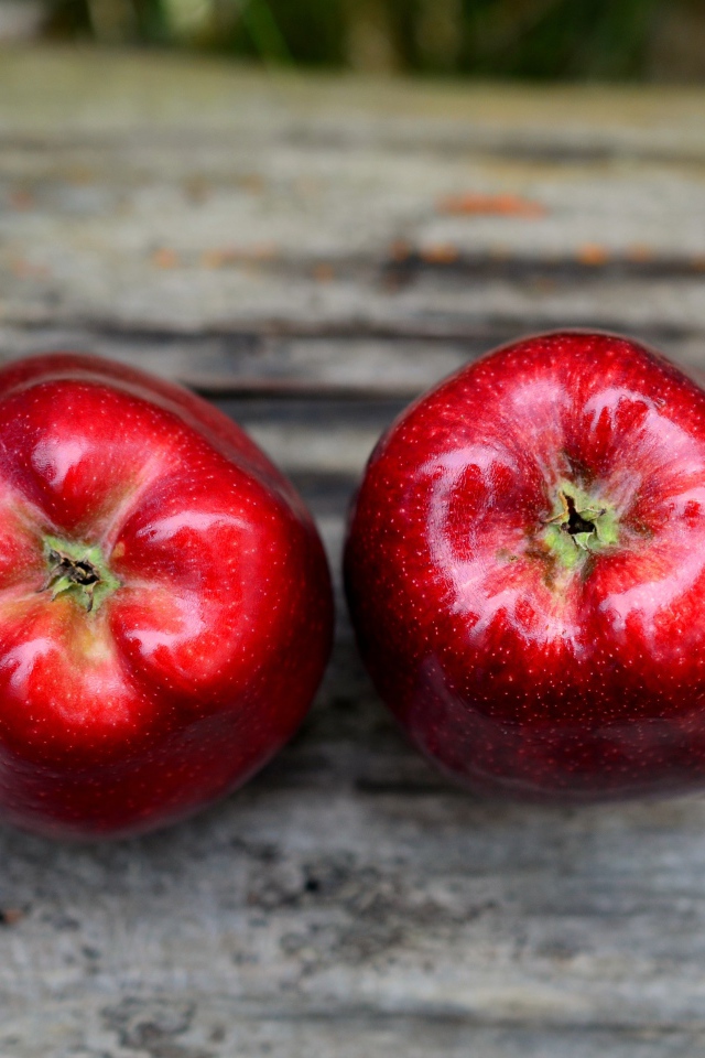Два больших красных яблока на деревянном столе