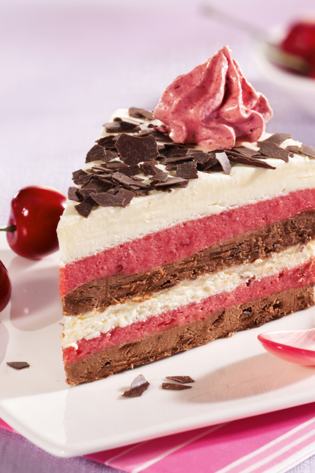 Кусок торта с вишневым и шоколадным кремом на белой тарелке