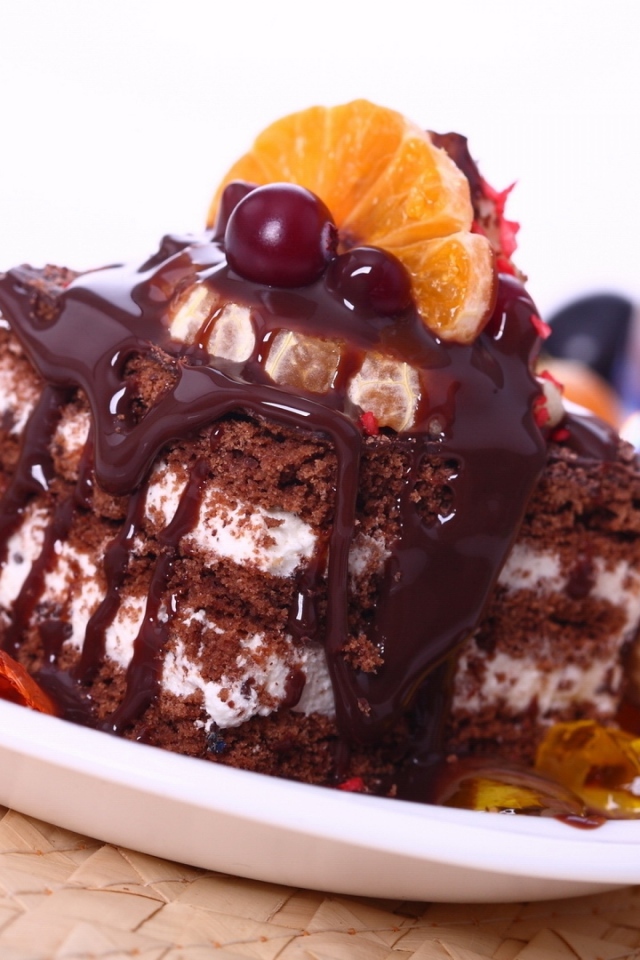Аппетитное пирожное с шоколадной глазурью, трубочками и мандаринами