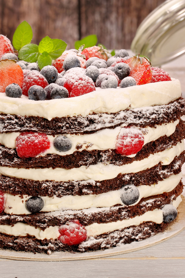 Аппетитный торт с кремом и ягодами посыпан сахарной пудрой