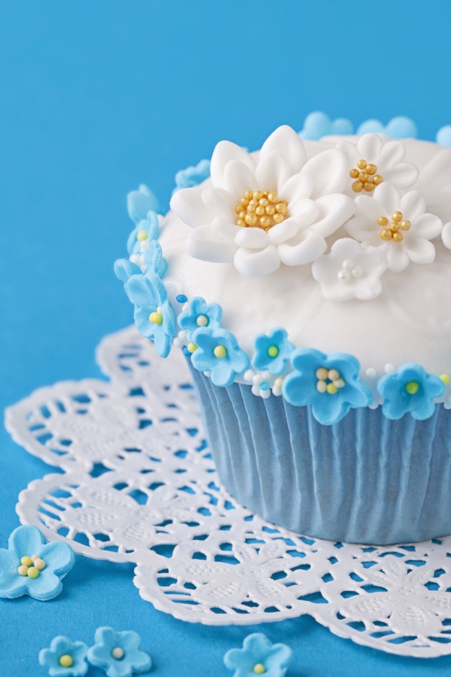 Аппетитный кекс украшен цветами на голубом фоне