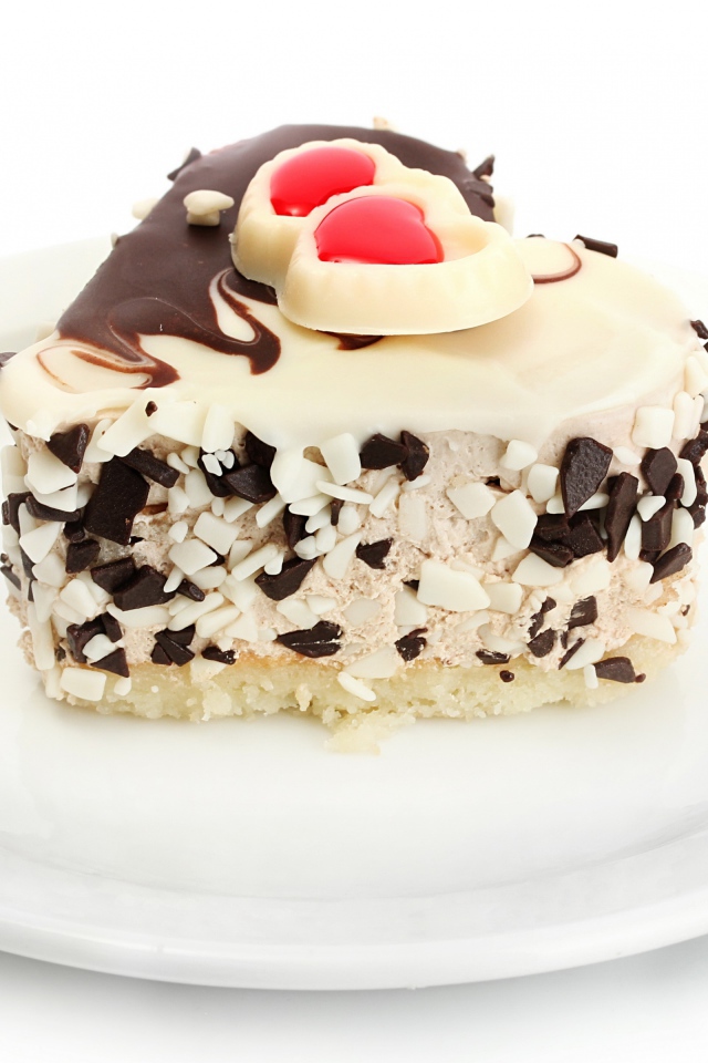 Аппетитное пирожное в форме сердца с шоколадом на белой тарелке