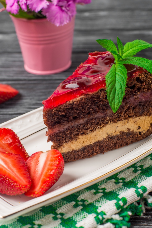 Аппетитный кусок торта на тарелке с ягодами клубники