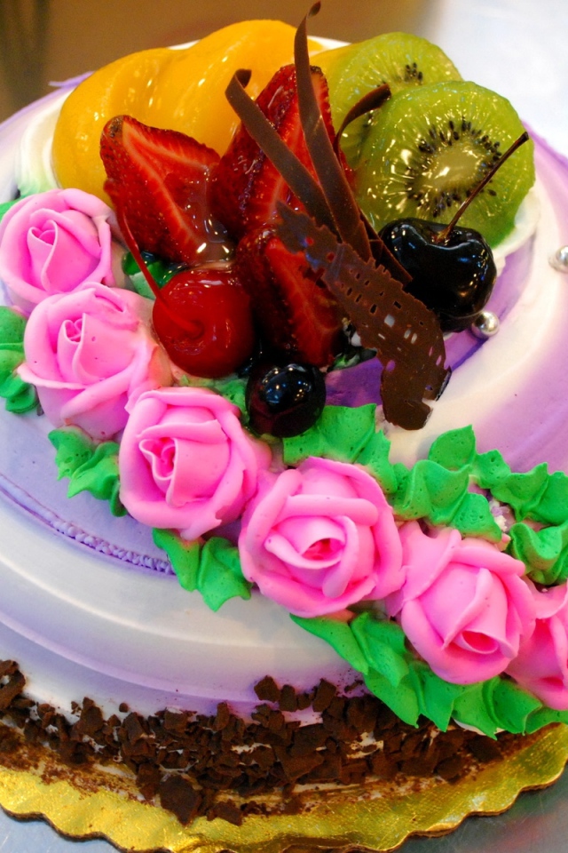Красивый торт с фруктами украшен розовыми розами из крема
