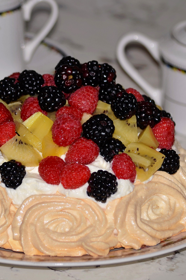 Торт с безе и свежими ягодами на столе 