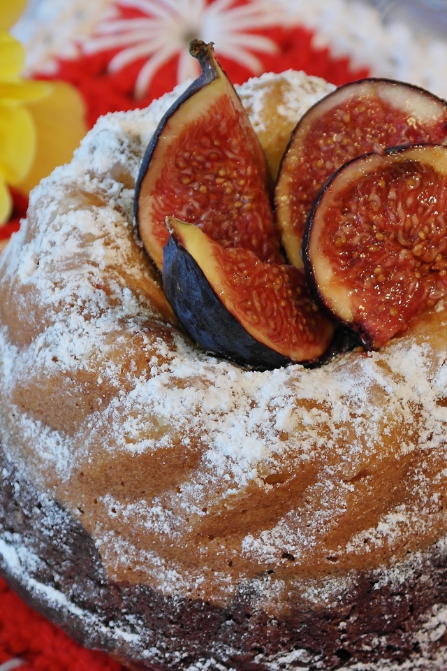 Кекс с инжиром и сахарной пудрой на столе с цветами