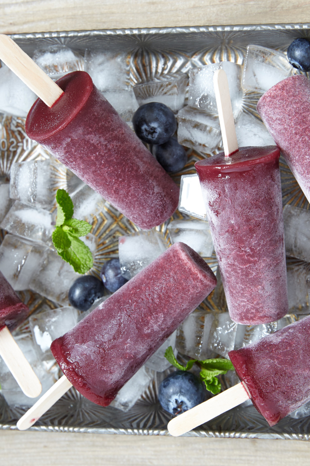 Вкусное черничное мороженое на палочке в лотке со льдом