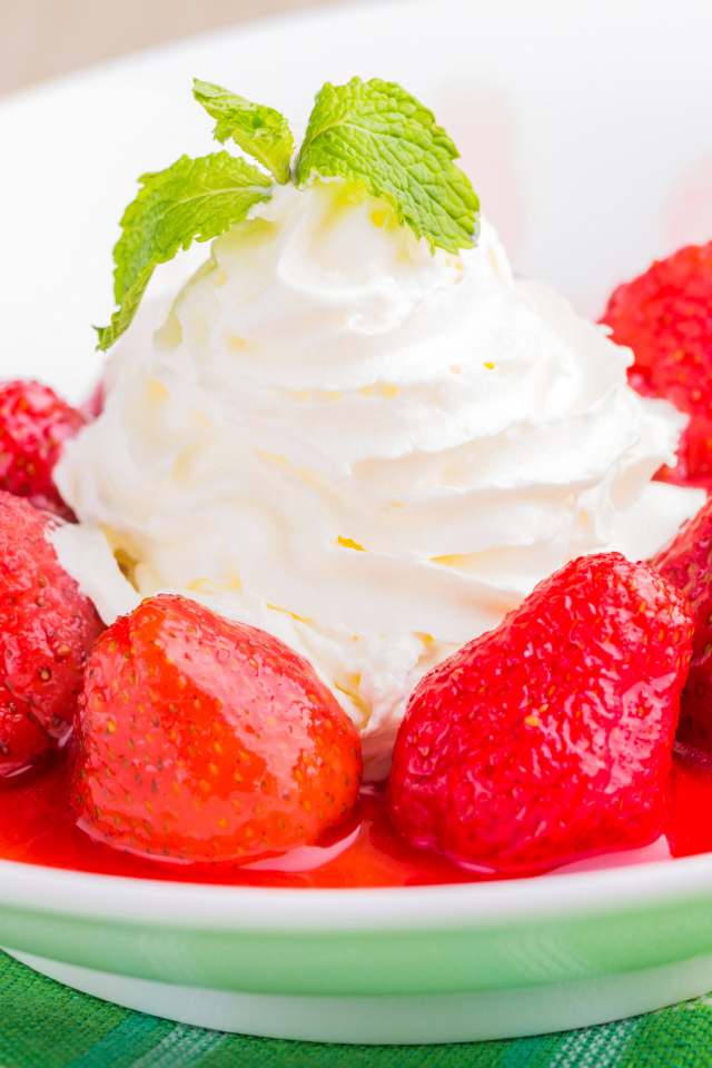 Вкусные сливки с клубникой на белой тарелке