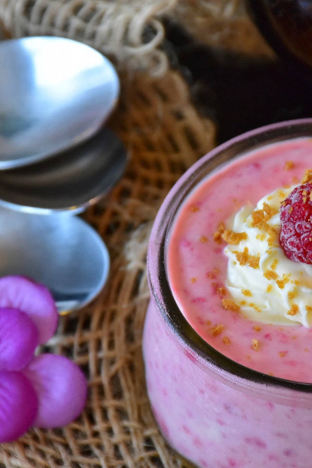 Десерт с малиной и кремом на столе с ложками