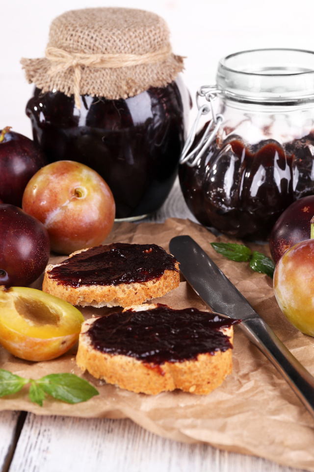 Свежие сливы и сливовый джем на столе 