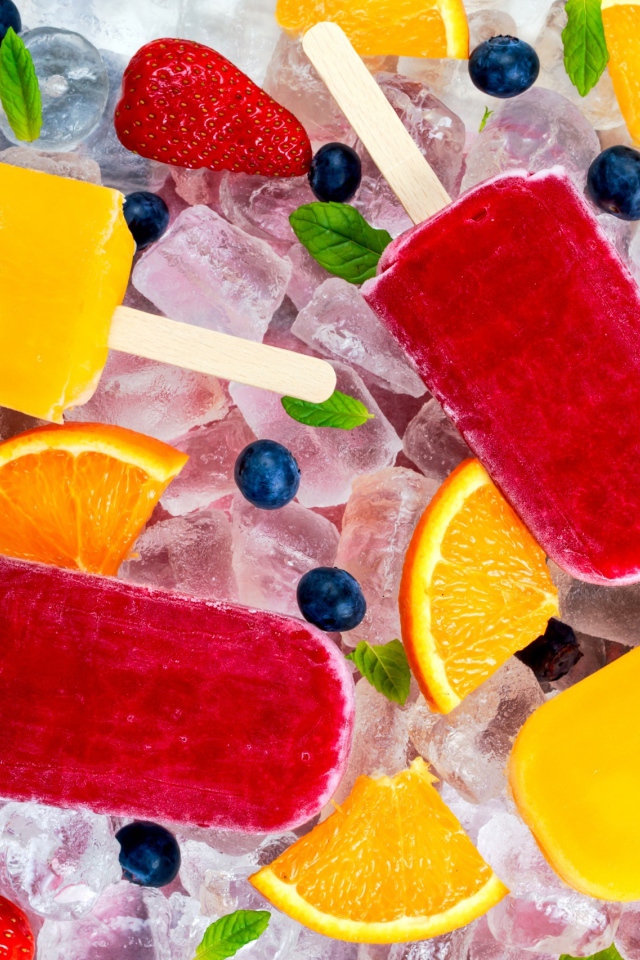 Разноцветное фруктовое мороженое с ягодами лежит на кусочках льда