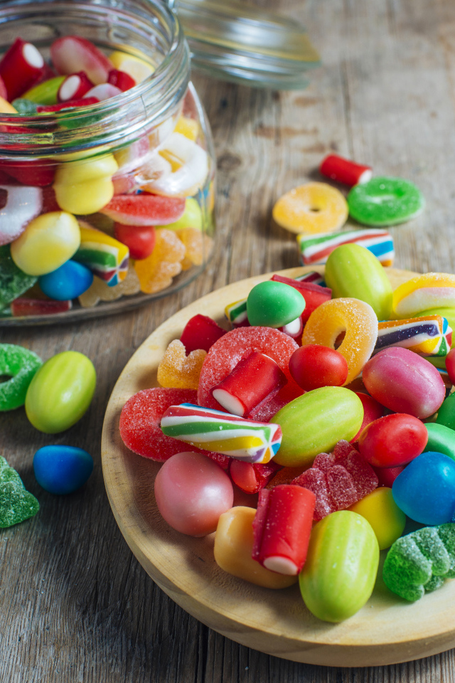 Разноцветные мармеладные конфеты в стеклянной банке на столе