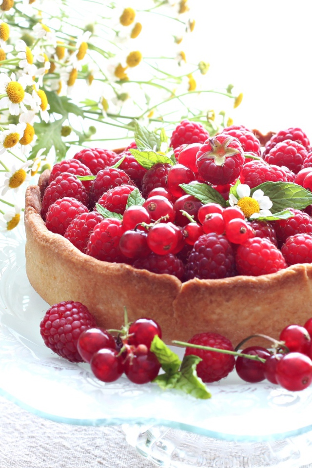 Пирог с ягодами малины и смородины на столе с ромашками