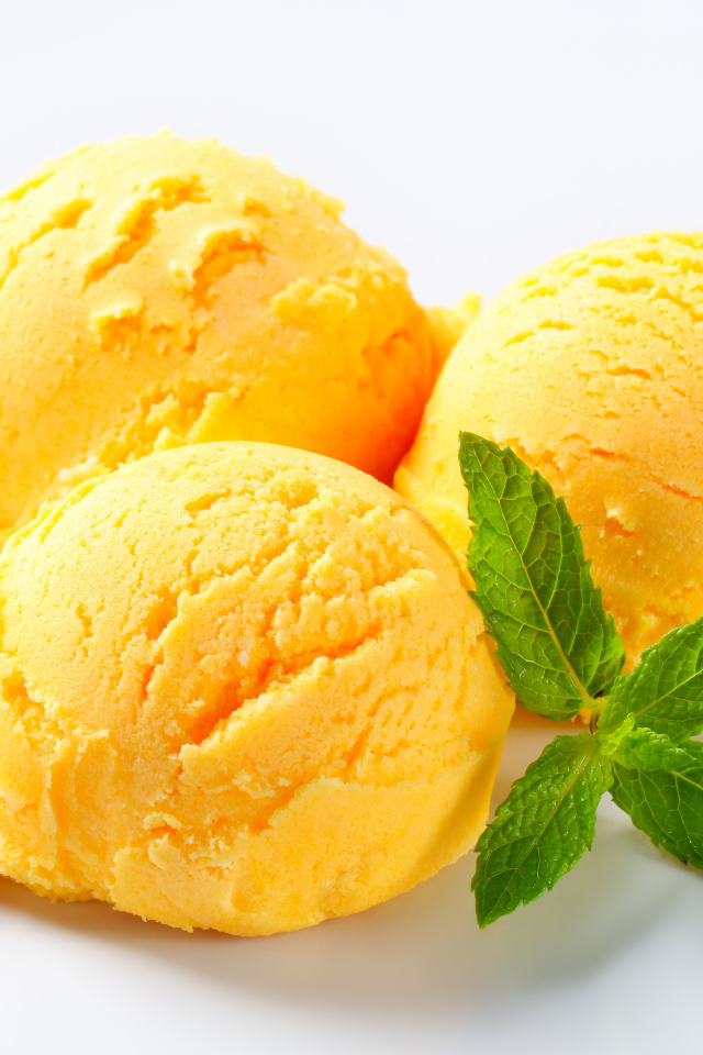 Три шарика фруктового мороженого с листиком мяты на белом фоне