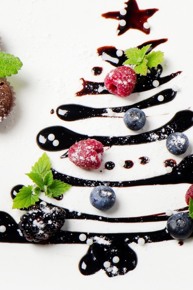 Три кекса и нарисованная шоколадом елка на белой тарелке