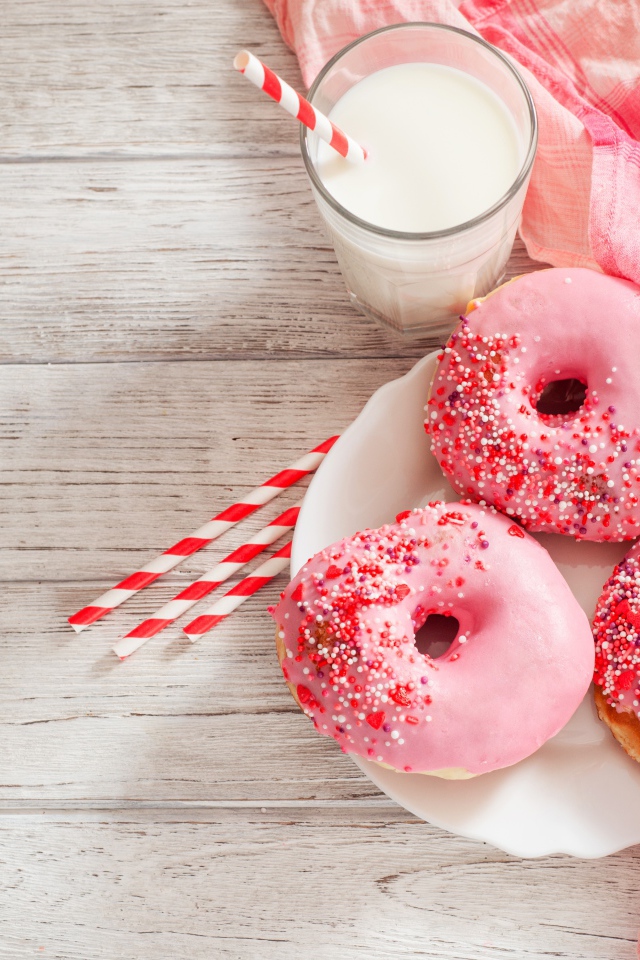 Три аппетитных пончика с розовой сахарной слазурью и стаканом молока