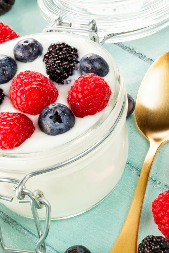 Йогурт со свежими ягодами малины, черники и ежевики в стеклянной банке на завтрак