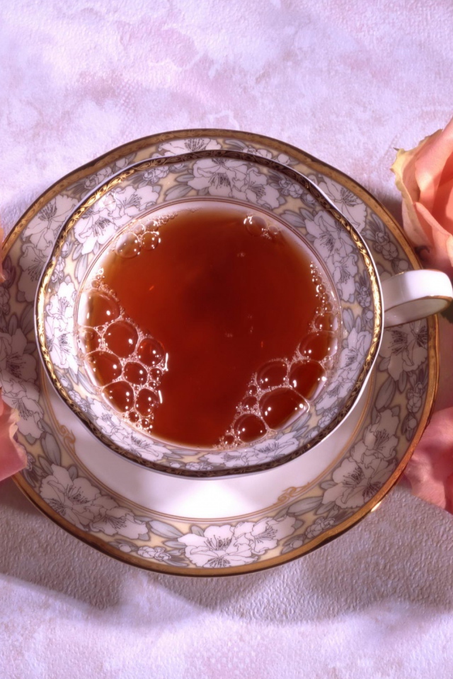 Красивая чашка черного чая на столе с розовыми розами