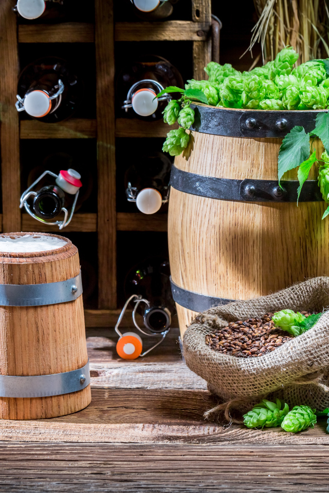 Бокал пива и деревянная бочка с хмелем на столе